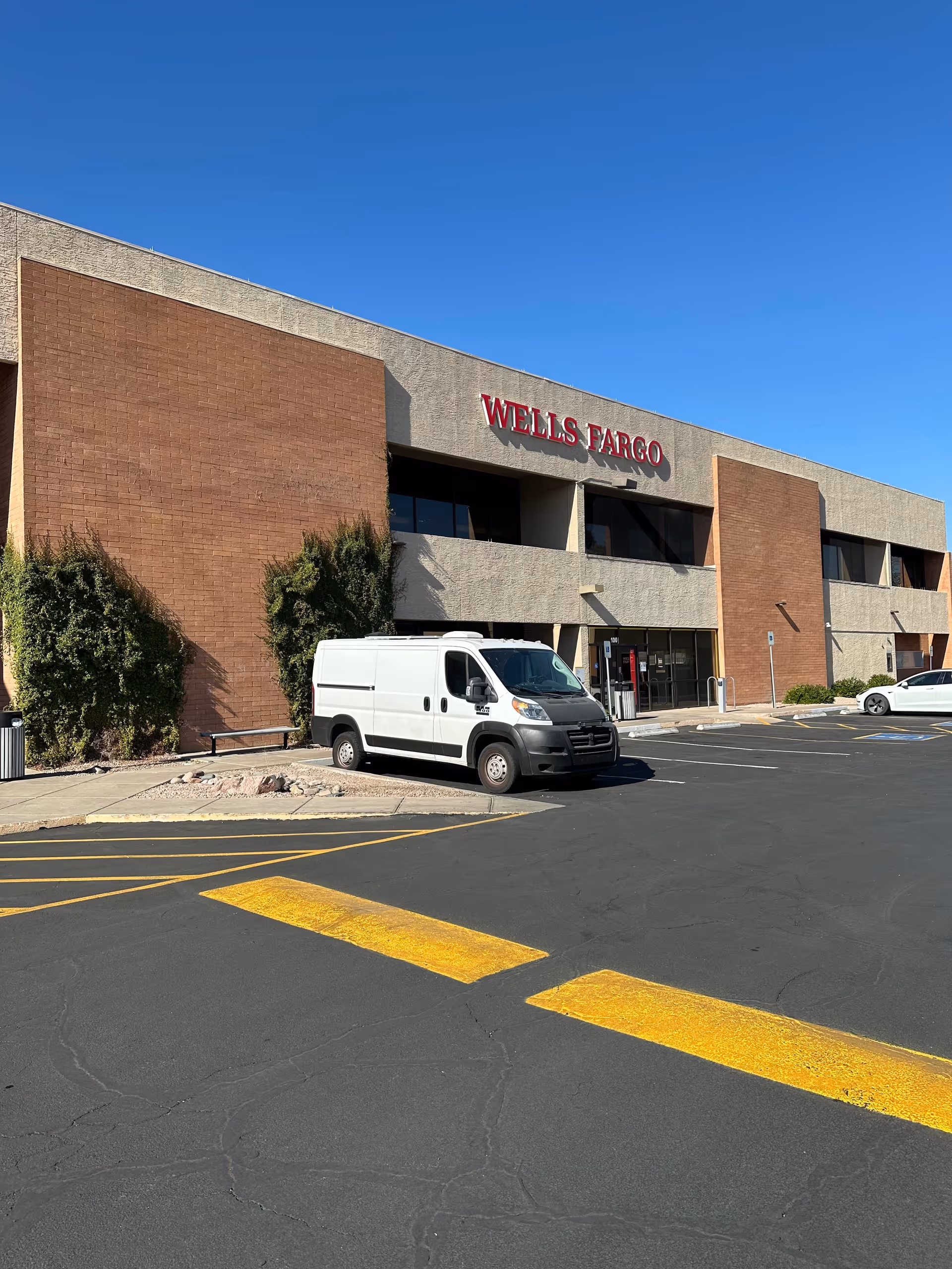 Exterior view of a Wells Fargo bank with a white van in the parking lot.