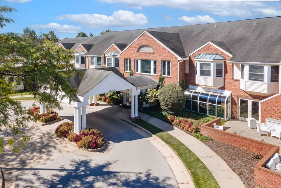 Front view of a brick senior living facility with a covered entrance and landscaping.