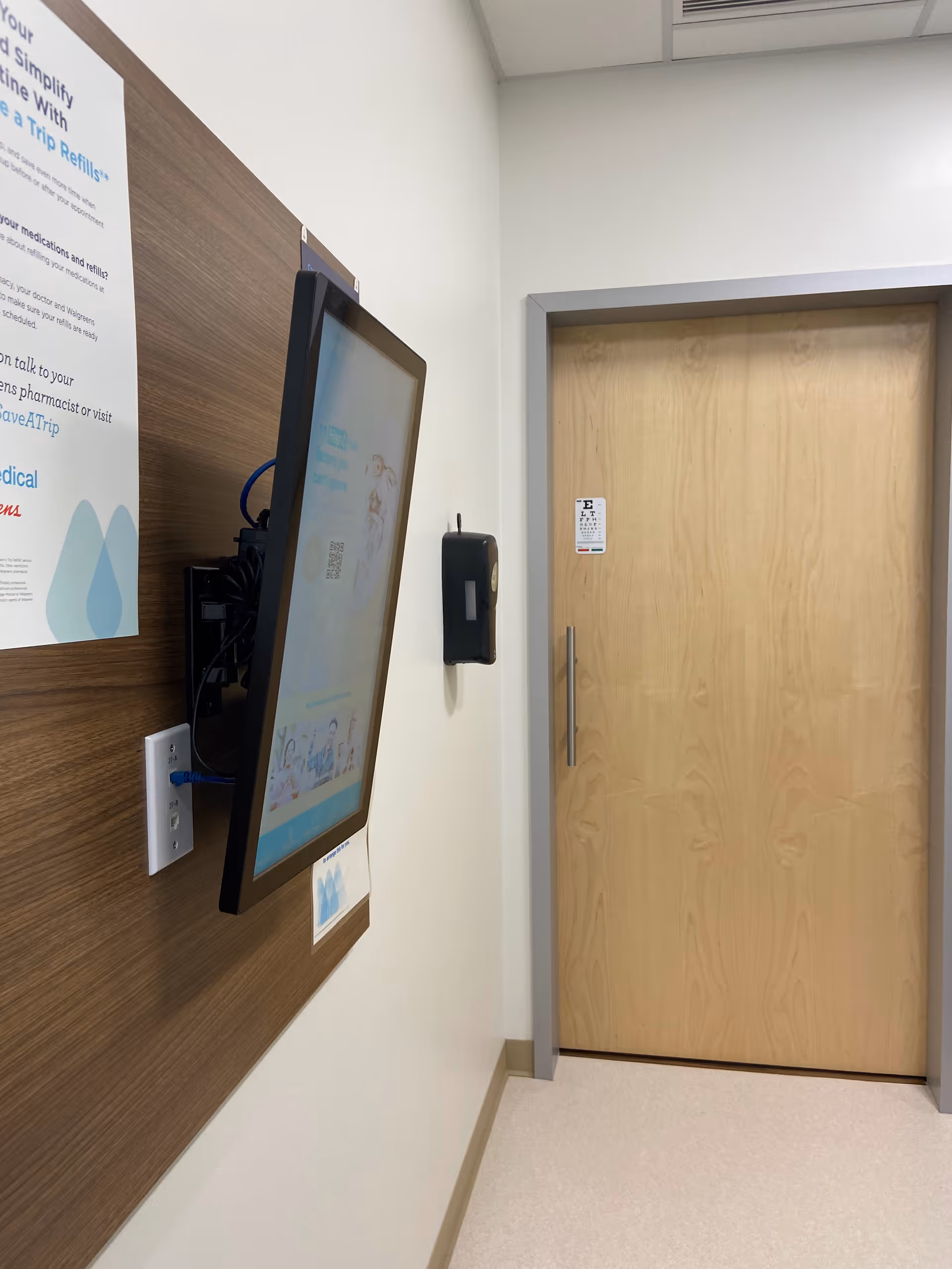 Corridor in a senior living facility with wall-mounted screen.