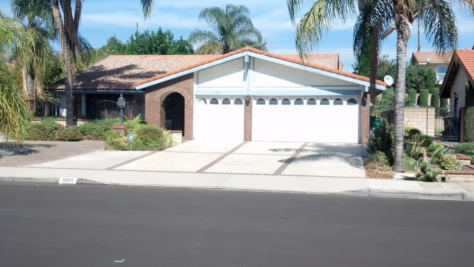 Front view of Genesis Manor IV building with a double garage and palm trees.