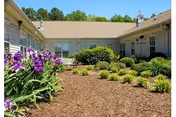 Exterior view of Summit of Lawrenceburg, showing a landscaped courtyard with shrubs and purple flowers.