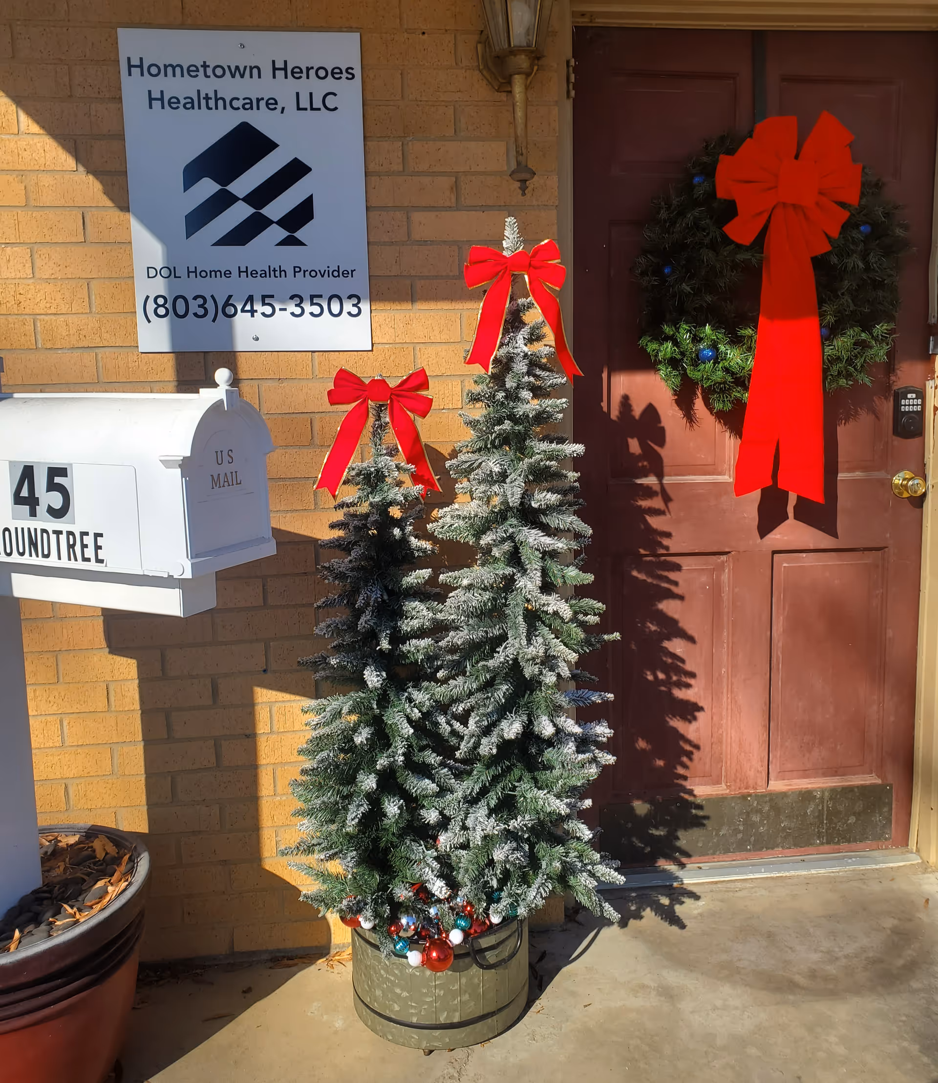 Front entrance of Hometown Heroes Healthcare with holiday wreath, small frosted trees, and mailbox.