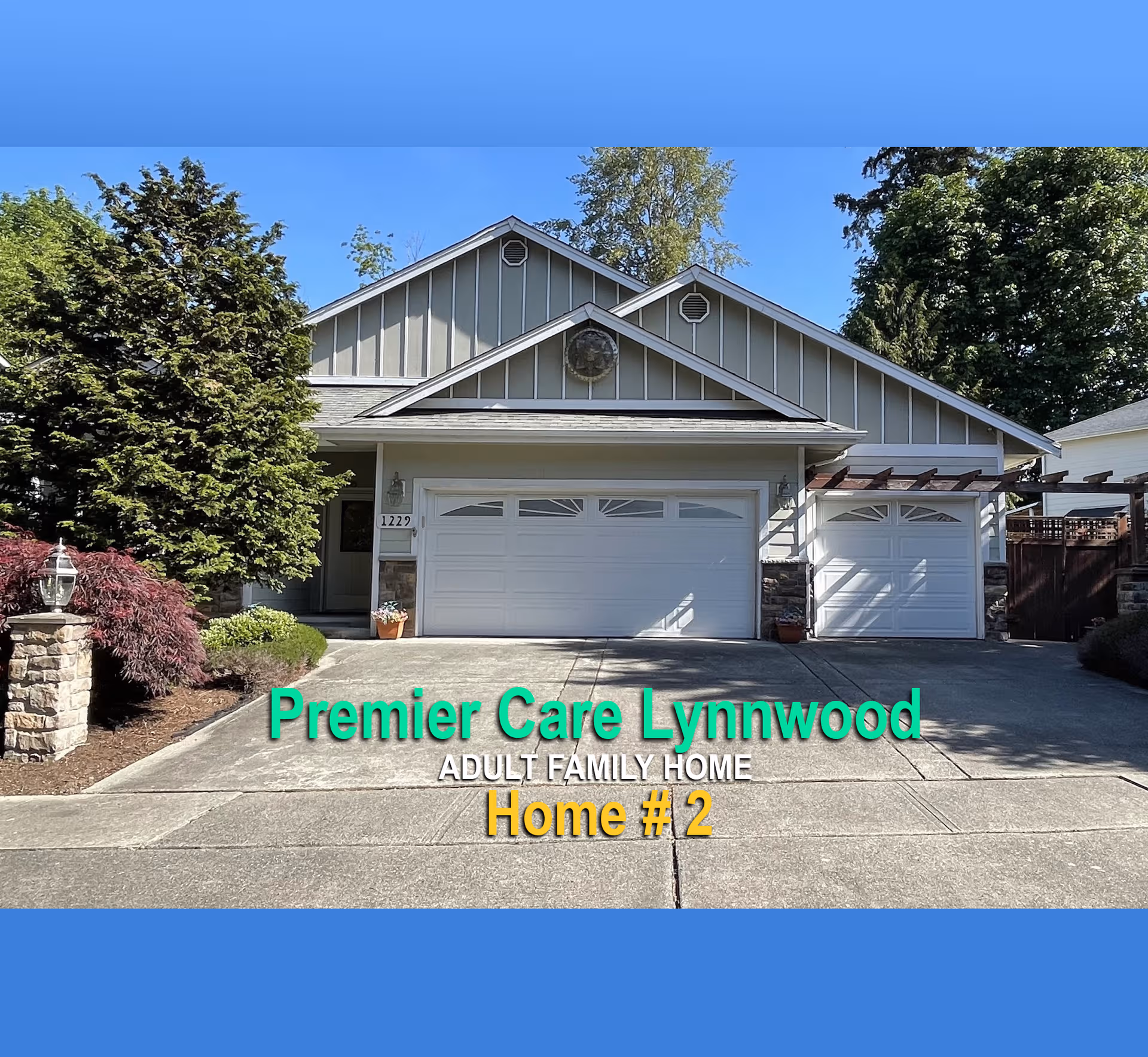 Exterior view of a grey, multi-garage home with landscaping and blue facility name overlay.