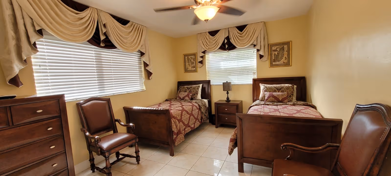Two twin beds with dark wood frames flank a central nightstand in a beige, well-lit bedroom.