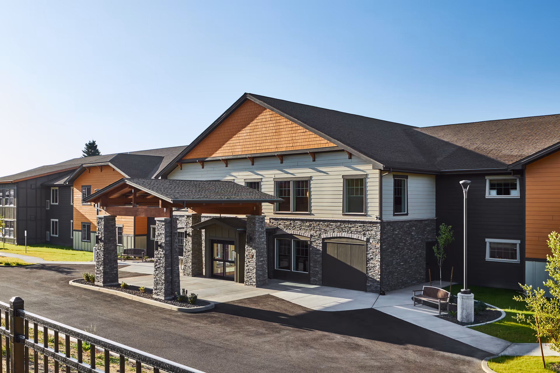 Front exterior of a modern assisted living facility with stone pillars and a covered entrance.