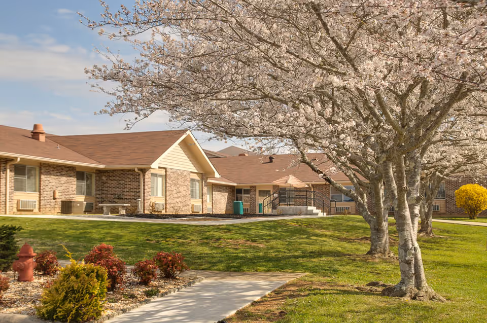 Front exterior of Life Care Center of Copper Basin with brick walls, blooming trees, and lawn.