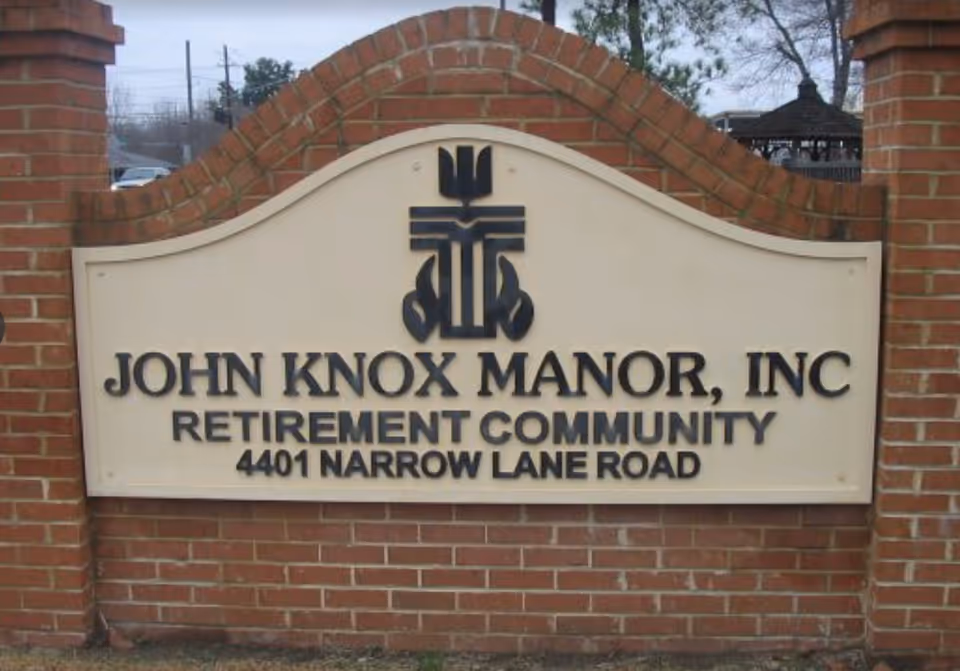 Brick entrance sign that reads "John Knox Manor, Inc Retirement Community 4401 Narrow Lane Road."