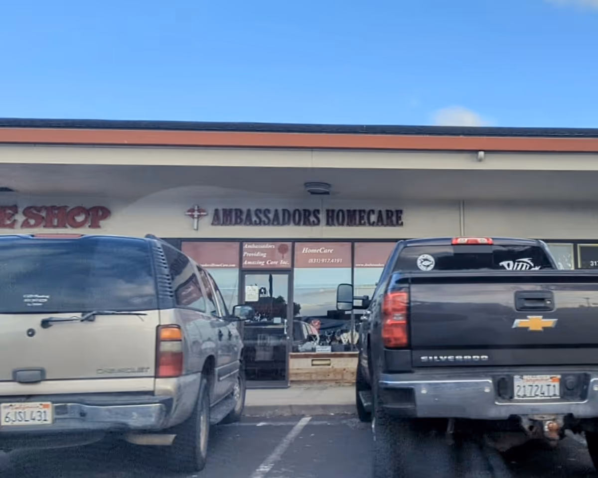 Exterior storefront with Ambassadors Homecare sign and two parked pickup trucks