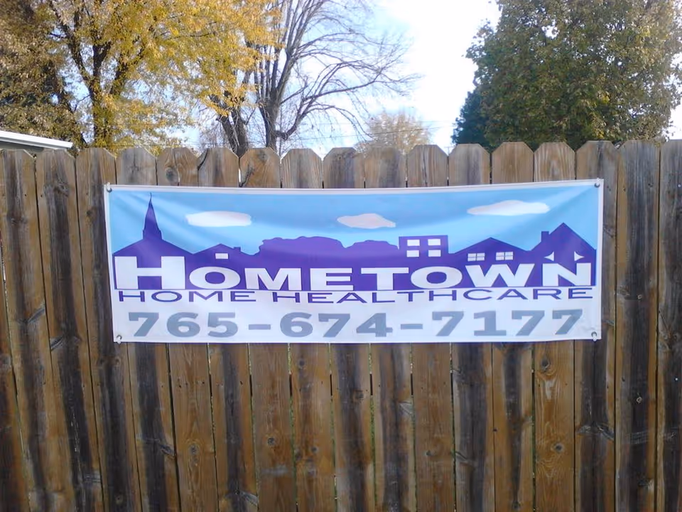 Blue and white banner advertising Hometown Home Healthcare fixed to a wooden fence.