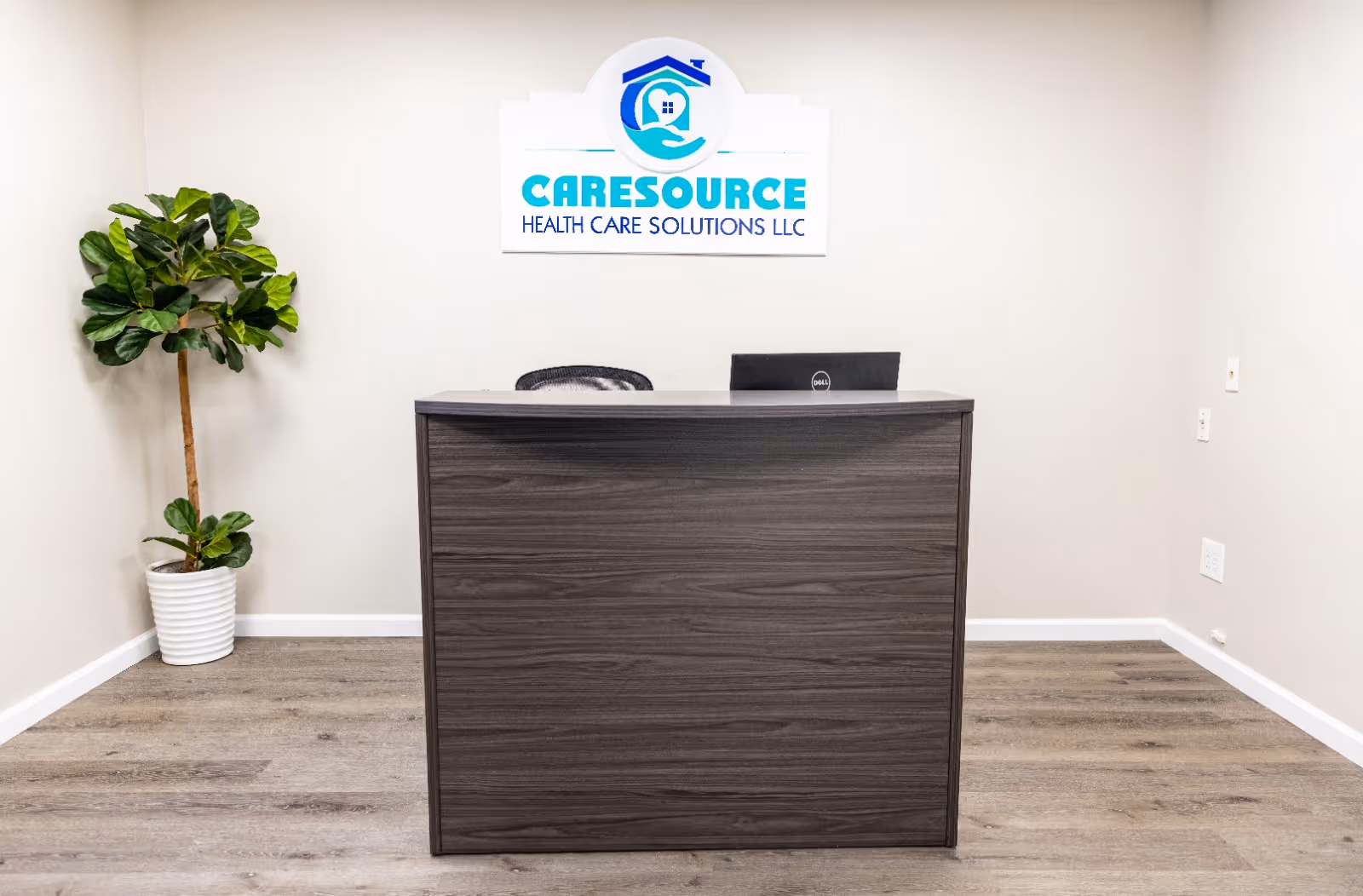 Reception desk in a beige interior with a CareSource sign and potted plant