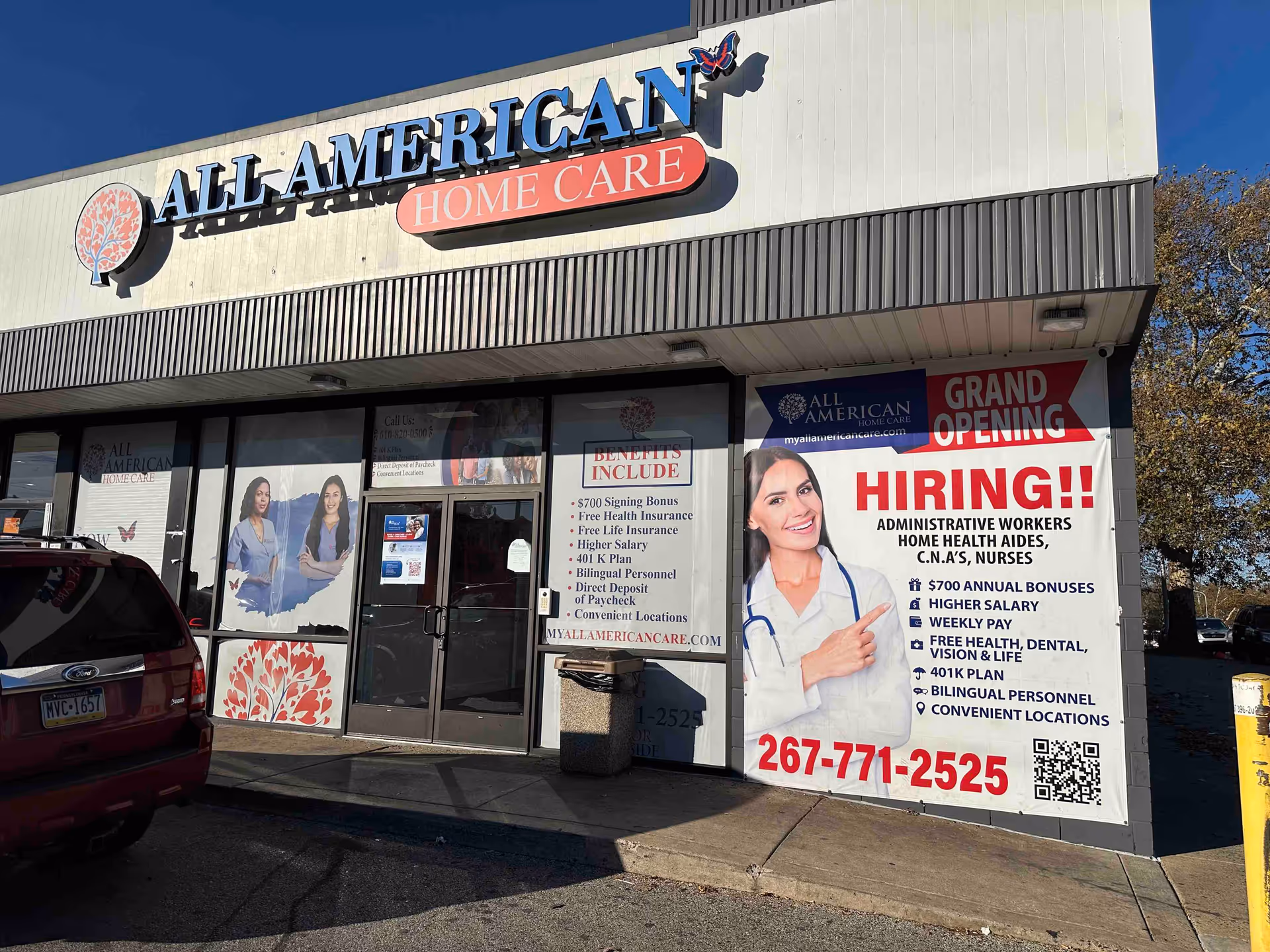 Exterior view of All American Home Care storefront with banners and Grand Opening sign.