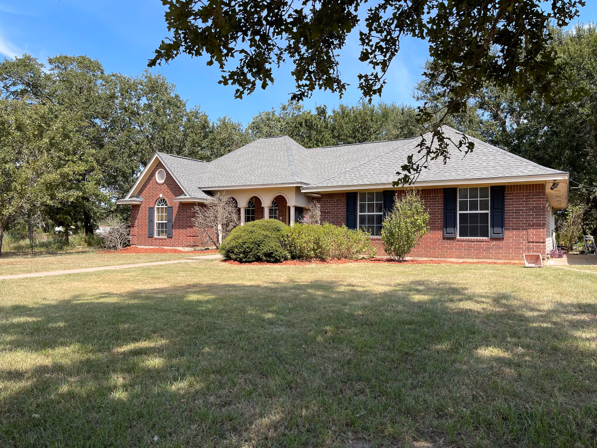 Brick, single-story senior living facility with arched entry and manicured lawn.