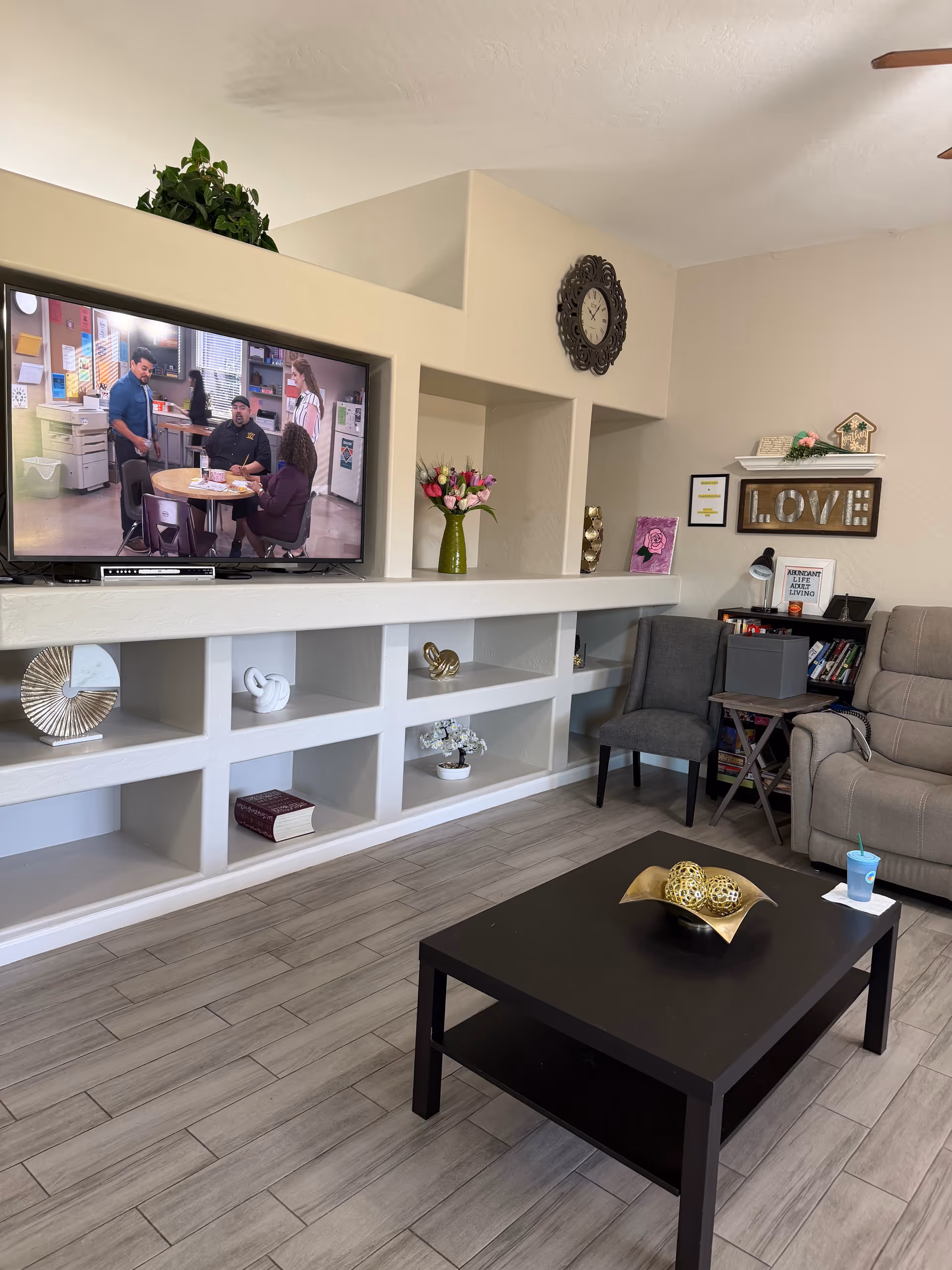 A cozy living area with a wall-mounted TV, shelves, and seating.