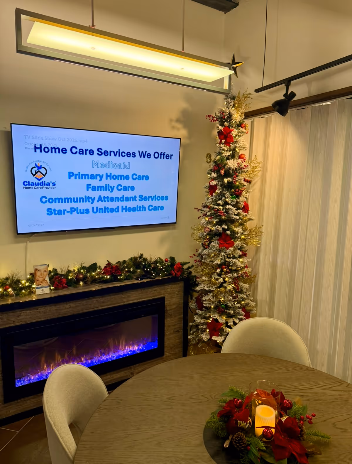 Well-lit lounge area with TV, holiday tree, fireplace, and round dining table.
