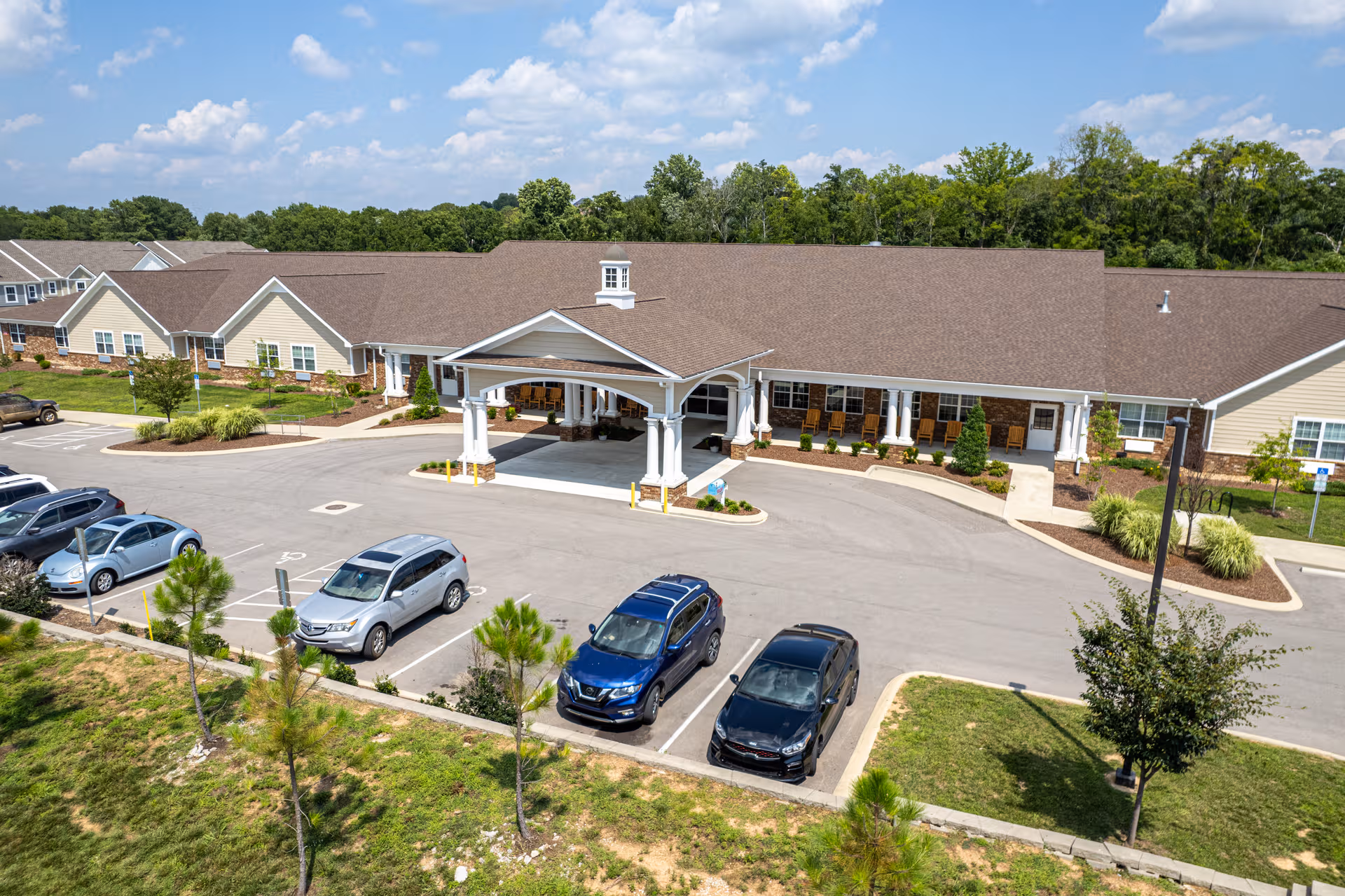 Exterior of a senior living facility with a covered entrance and parking.