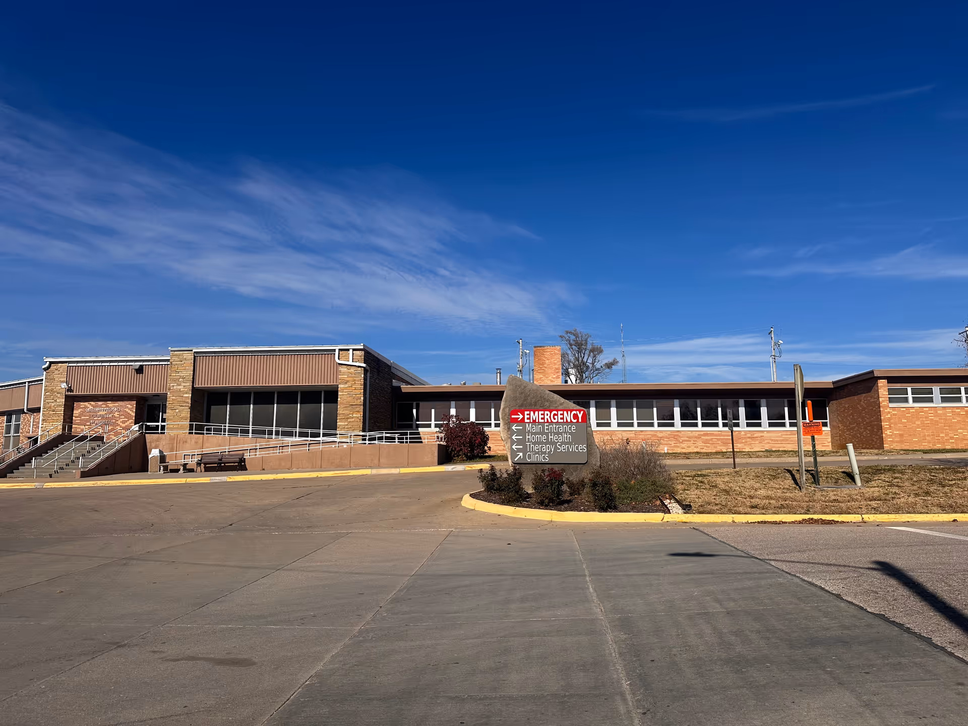 Exterior view of Greenwood County Hospital with emergency sign and blue sky.