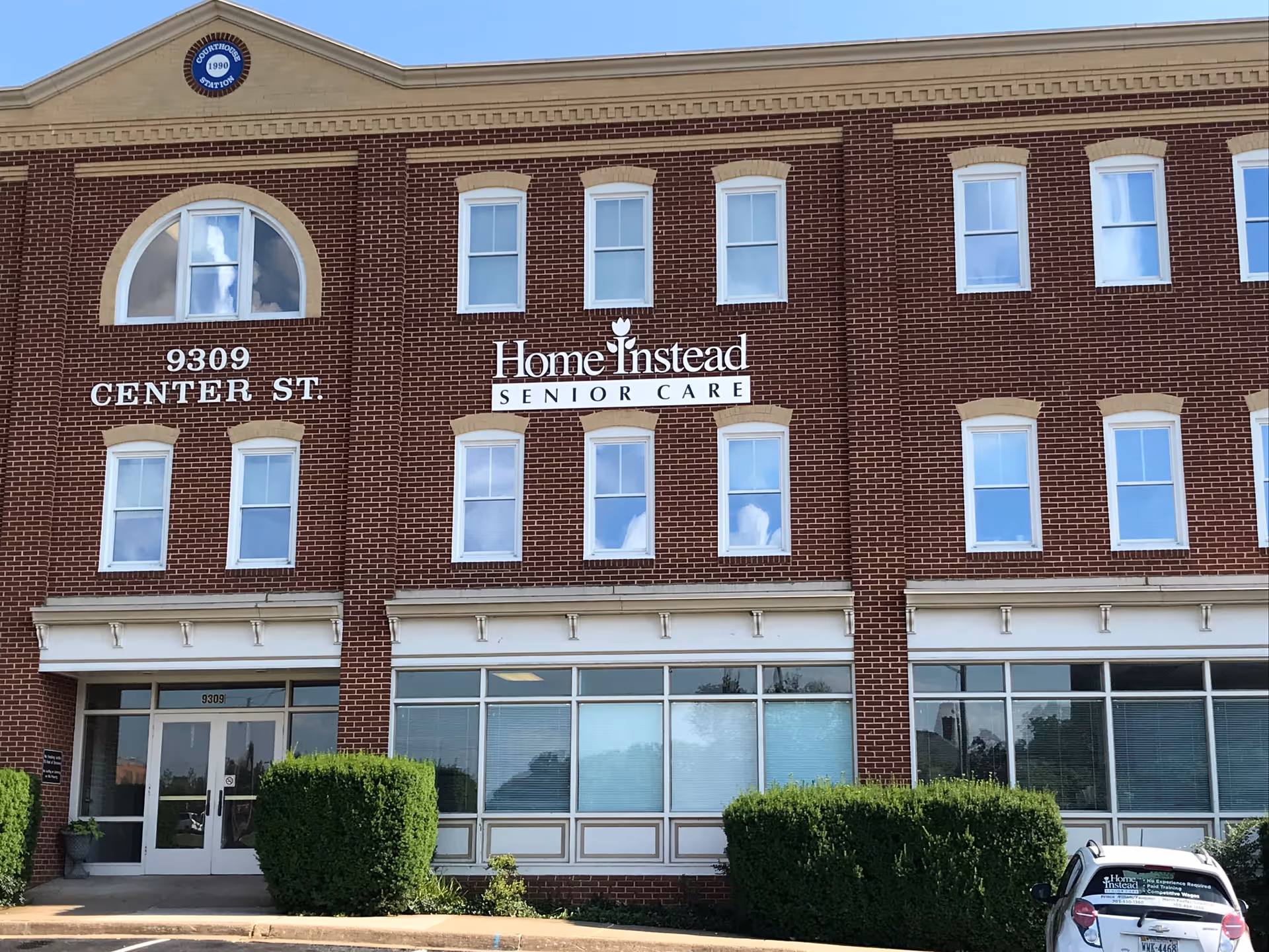 Brick three-story building with Home Instead Senior Care sign and glass entrance.
