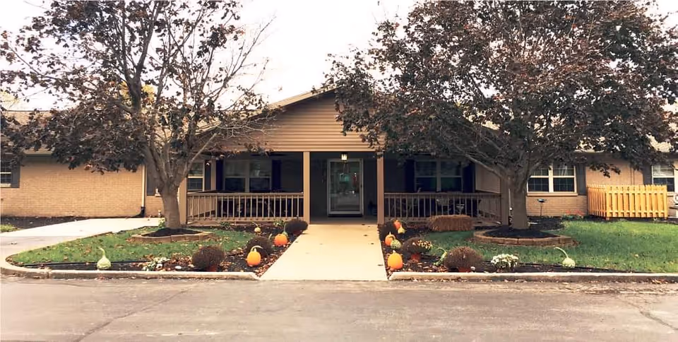 Front view of a single-story senior living facility with pumpkins and fall landscaping.