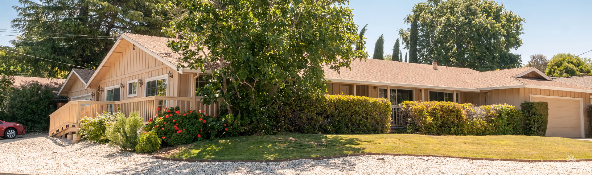 Front exterior of a single-story ranch-style building with a wheelchair ramp, garage, and landscaped lawn and shrubs.
