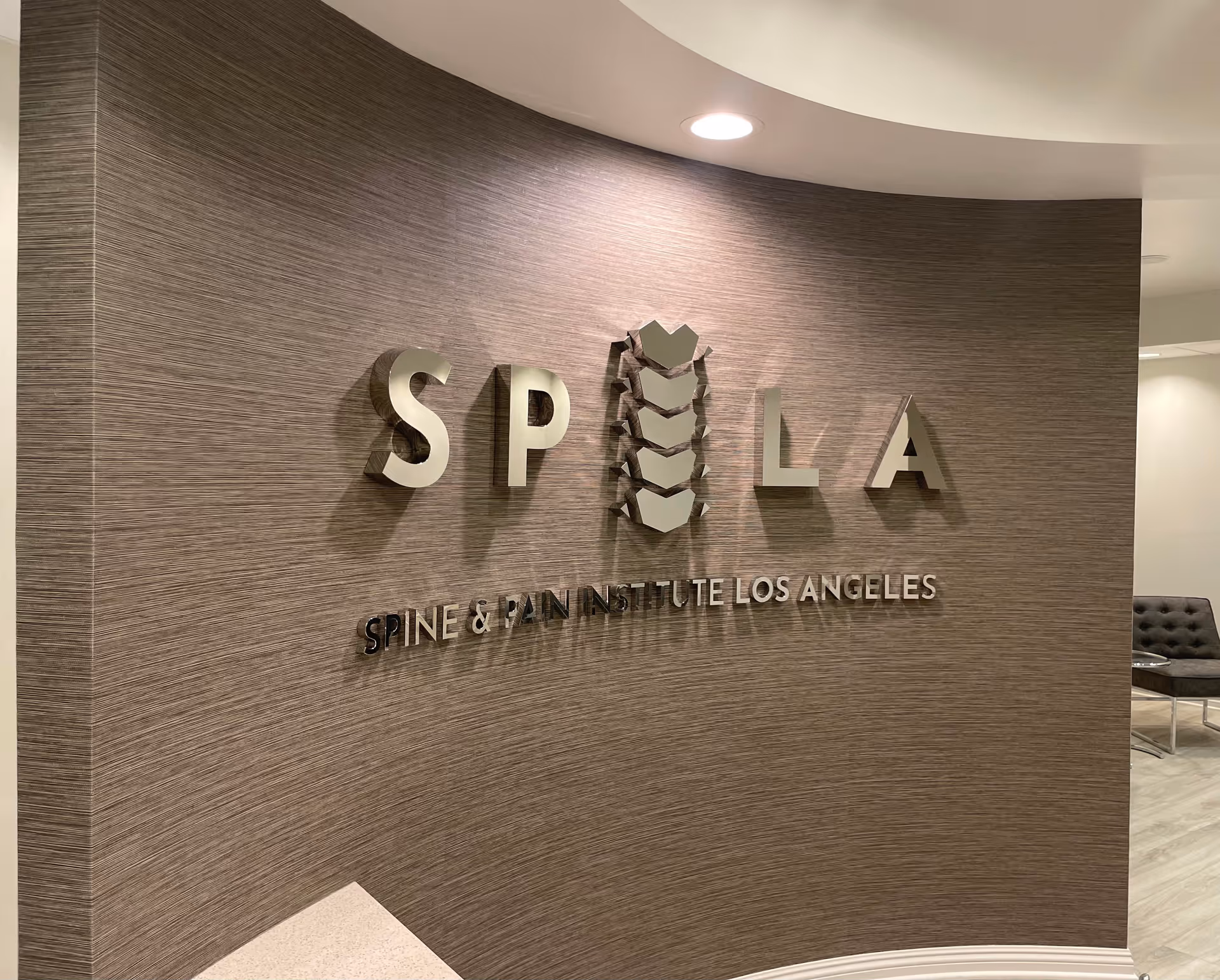 Interior wall with SPINE & PAIN INSTITUTE LOS ANGELES sign and seating nearby.