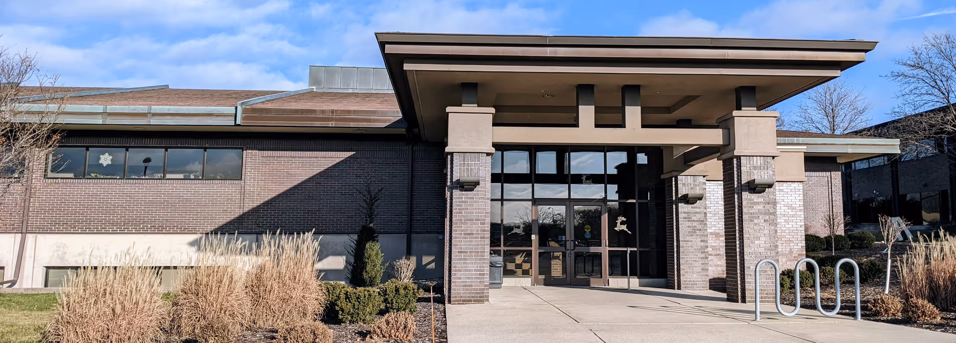 Front entrance of Castle Hospice building with brick exterior, glass doors, and covered walkway.