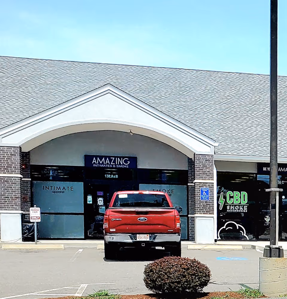 Red pickup truck parked in front of a strip mall with AMAZING storefronts