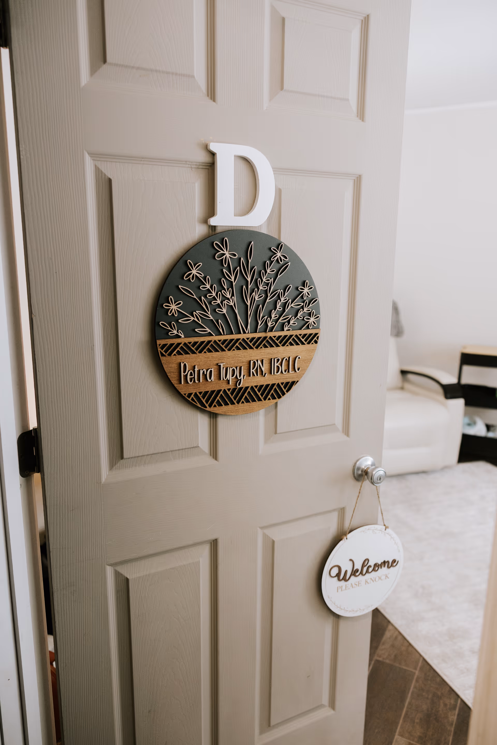 Interior doorway with round botanical sign and welcoming plaque beside door knob.