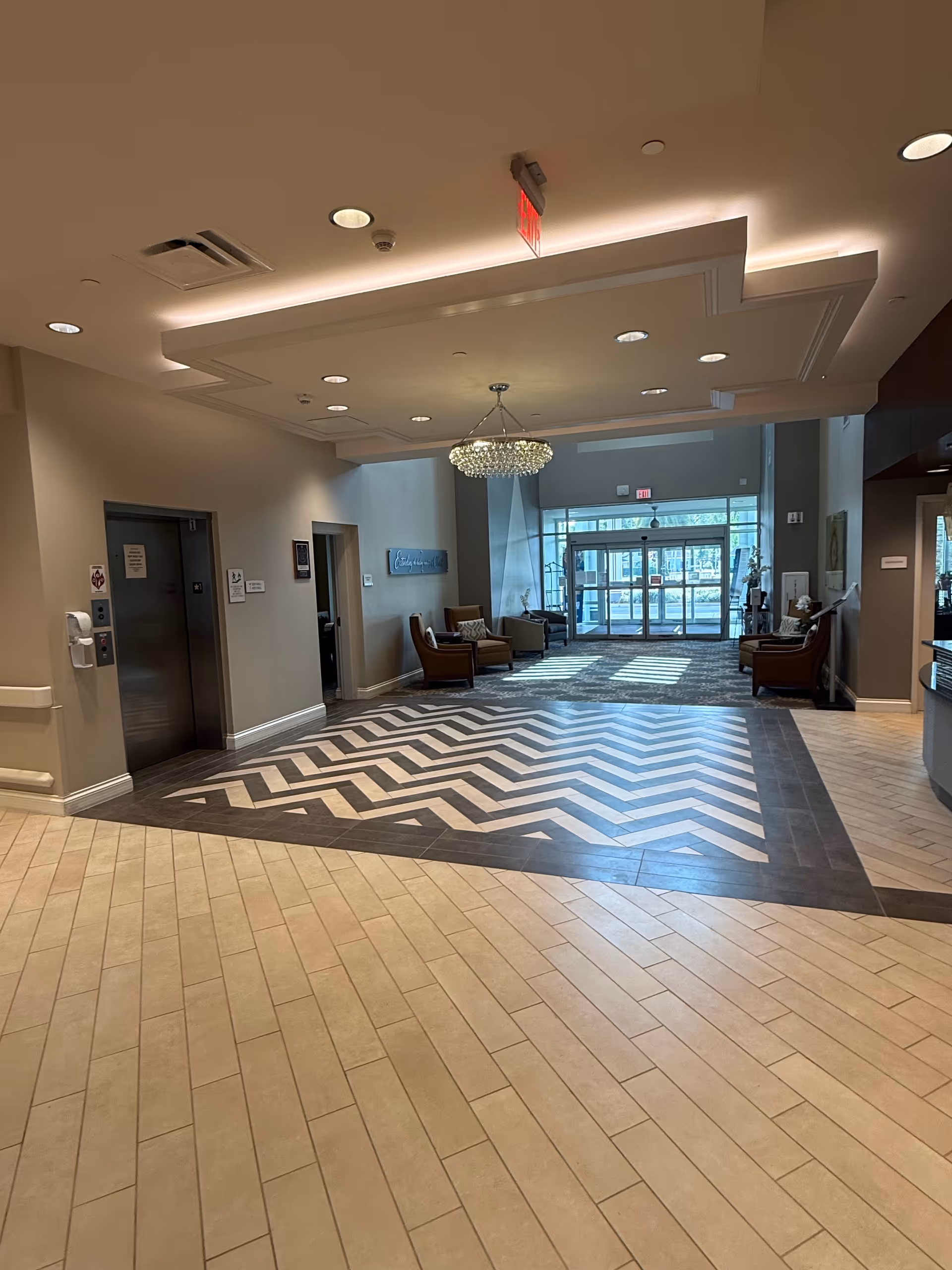 Bright hotel-style lobby at Solaris Healthcare Celebration with chevron floor, chandelier, and seating.