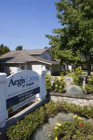 Exterior view of Aegis Living of Issaquah with sign, landscaping, and entry walkway.