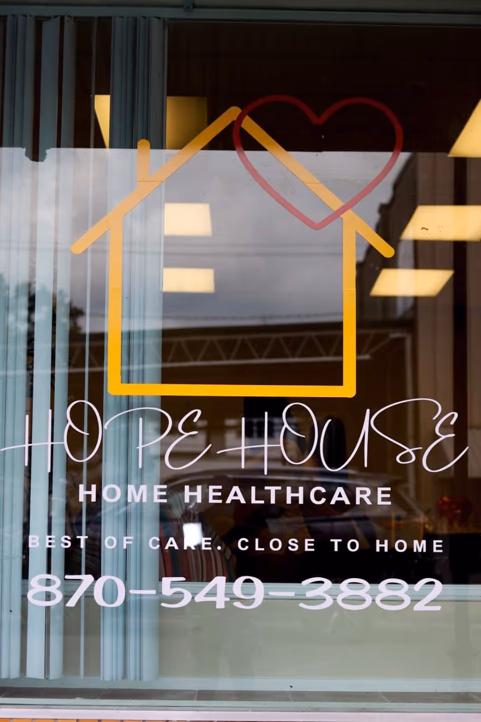 Window sign for Hope House Home Healthcare featuring a yellow house outline and heart.