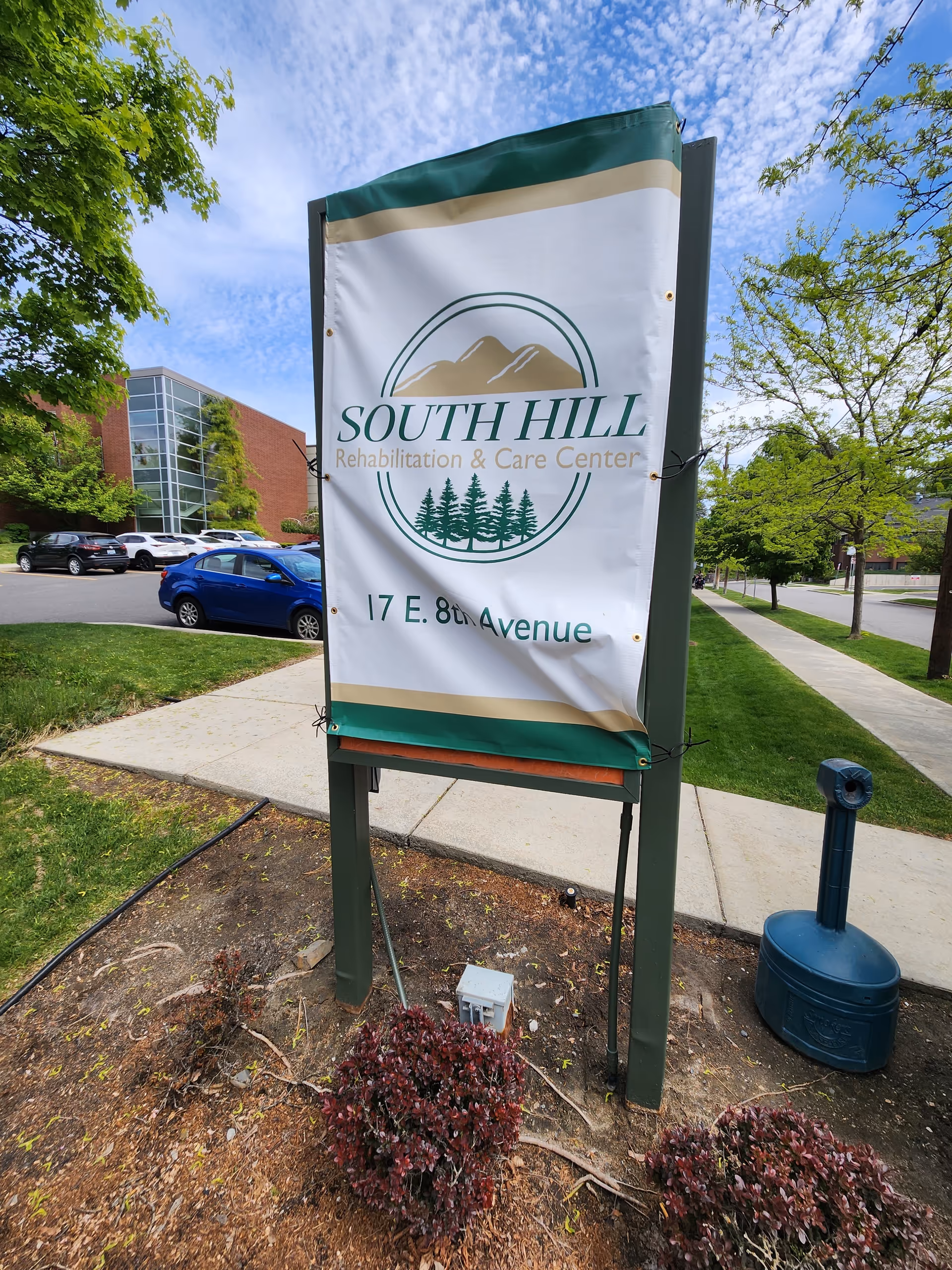 Outdoor sign for South Hill Rehabilitation & Care Center along a sidewalk.