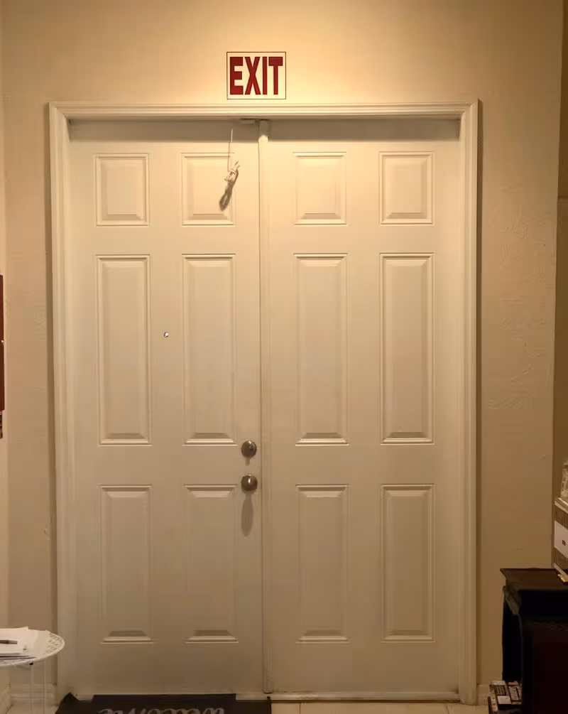 Double white interior doors with an 'EXIT' sign above in a hallway.