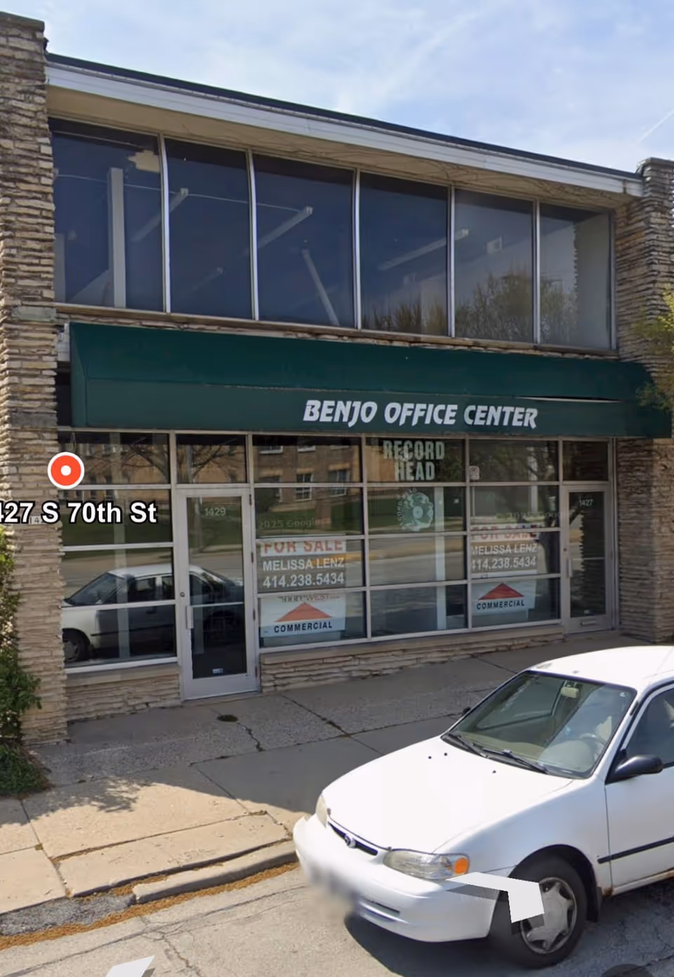 Storefront with a green awning reading BENJO OFFICE CENTER and a white car parked outside.