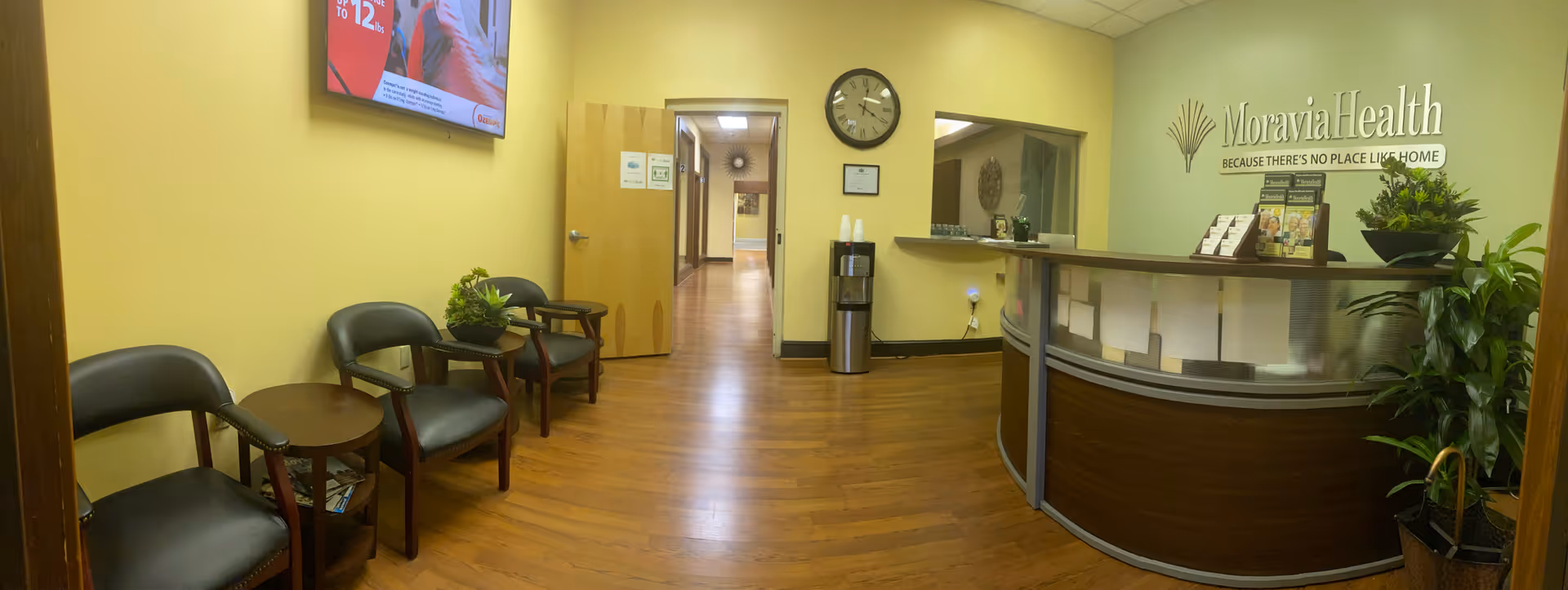 Reception lobby with curved desk, seating area, and Moravia Health signage.