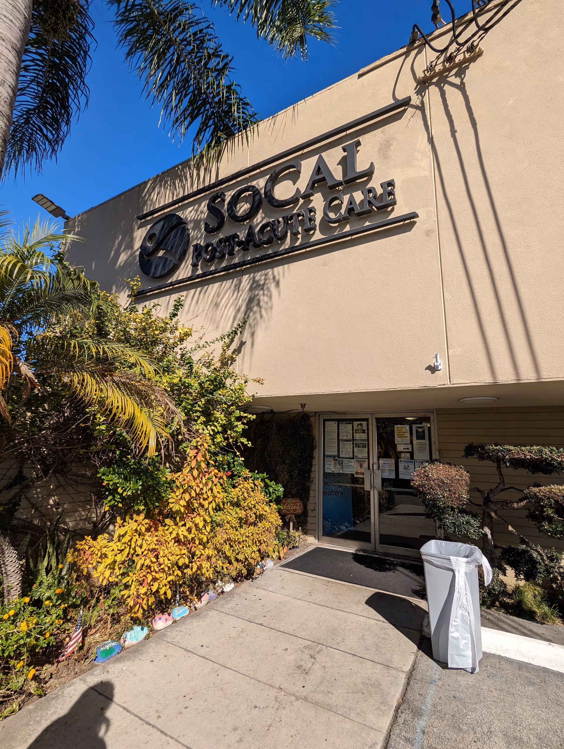 Front view of SoCal Post Acute Care building with signage and tropical landscaping