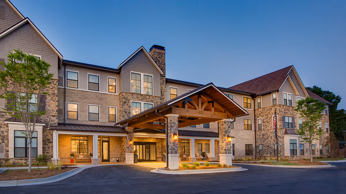 Stone-faced senior living facility exterior with a covered entrance and circular driveway
