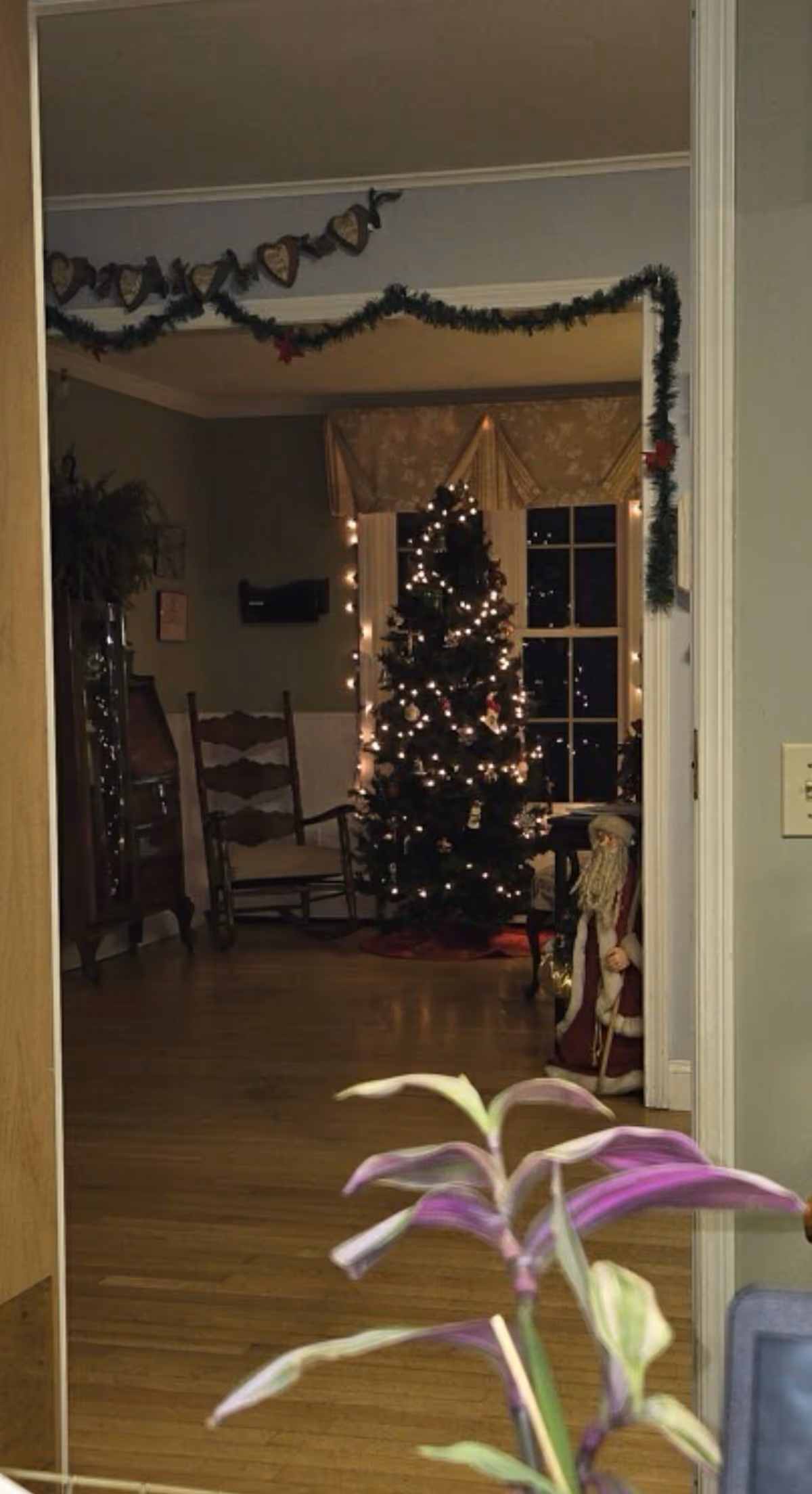 A warmly lit indoor living area with a Christmas tree, garlands, and holiday decor.