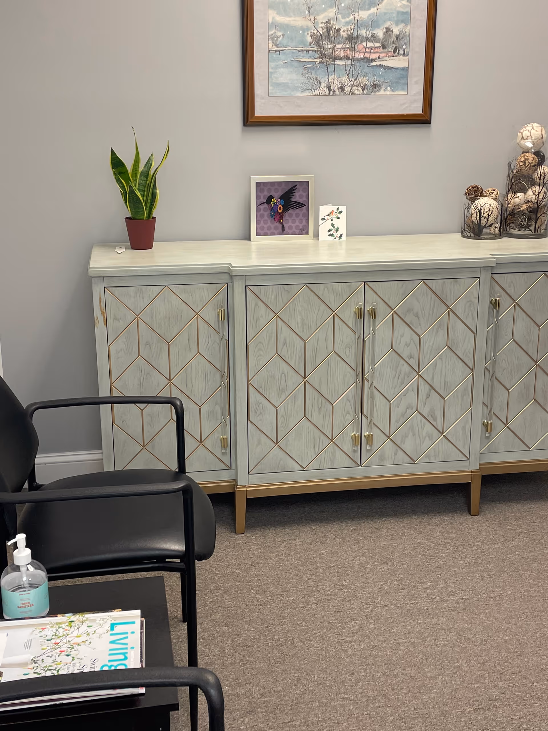 Light gray cabinets with geometric panels along wall, decorative items, and black chairs in waiting area.