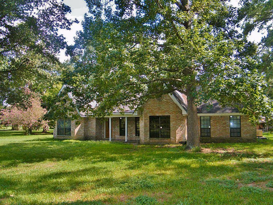 Brick building of Personal Care Home of Grace Manor with large trees and a front lawn