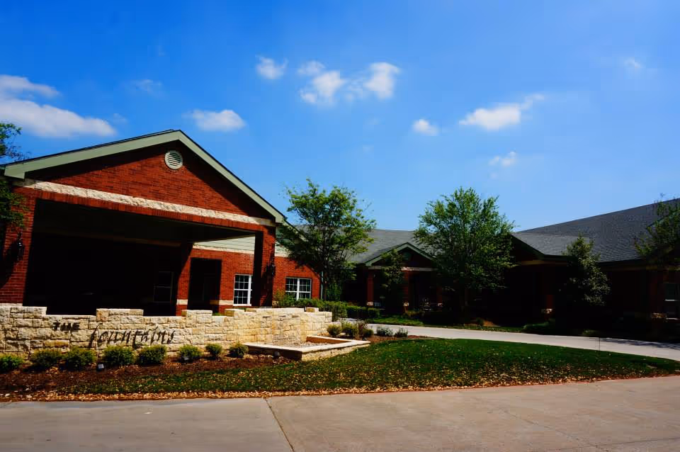 Front view of a red brick senior living facility with stone accents and landscaping.