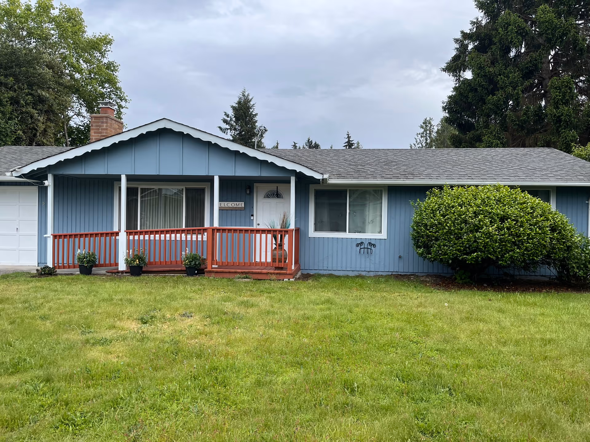 Blue single-story building with a front porch and green lawn.