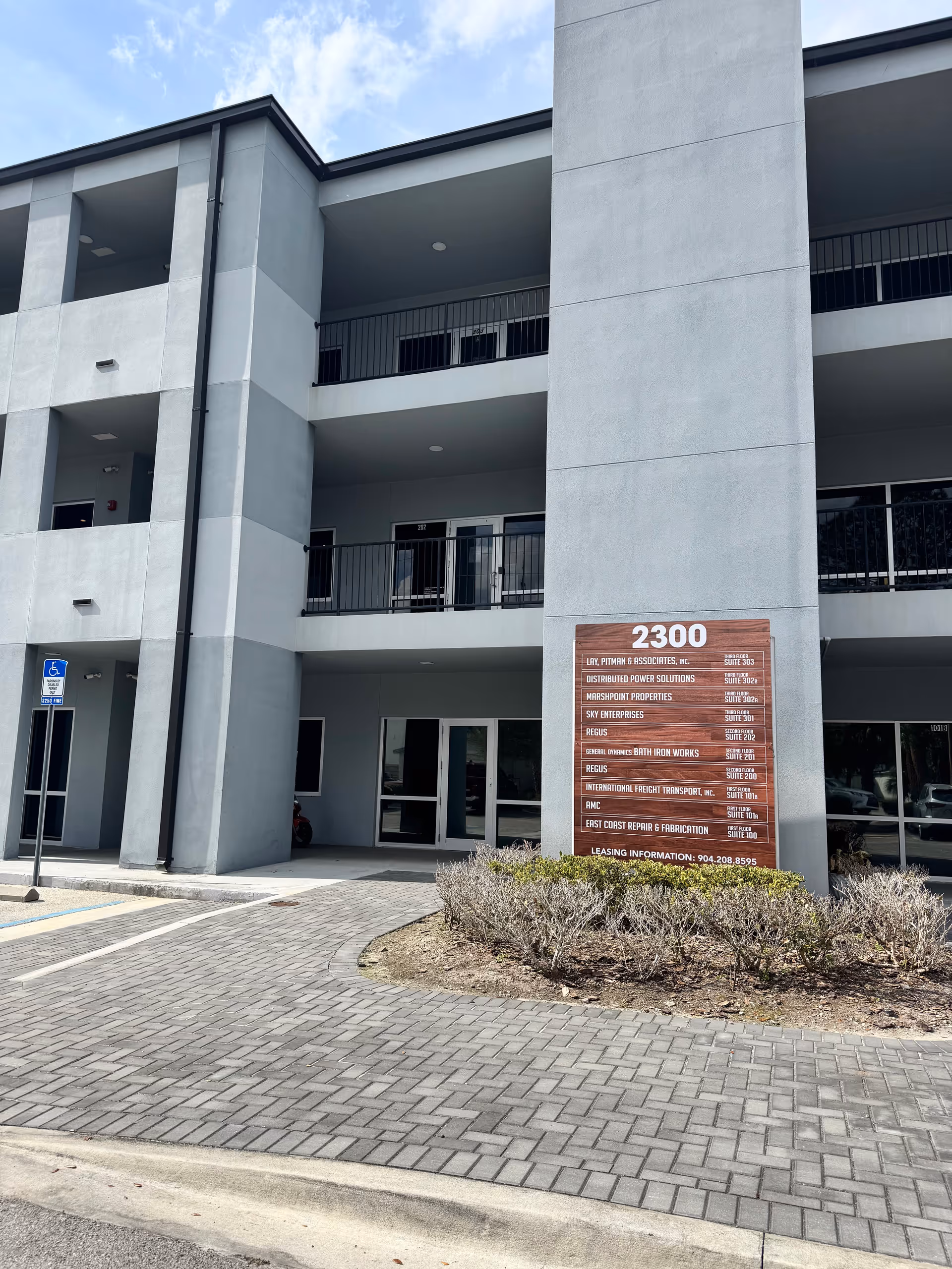 Modern multi-story building exterior with balconies and a large tenant sign at the entrance.