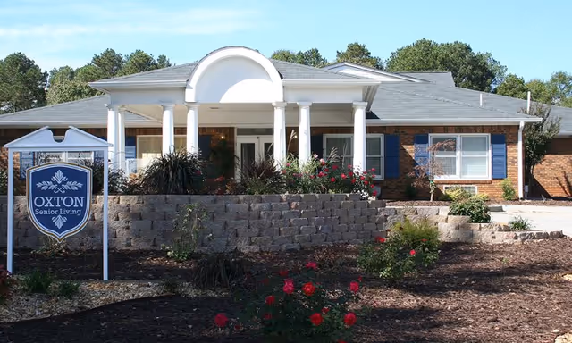 Front view of a senior living facility with columns and a landscaped entrance