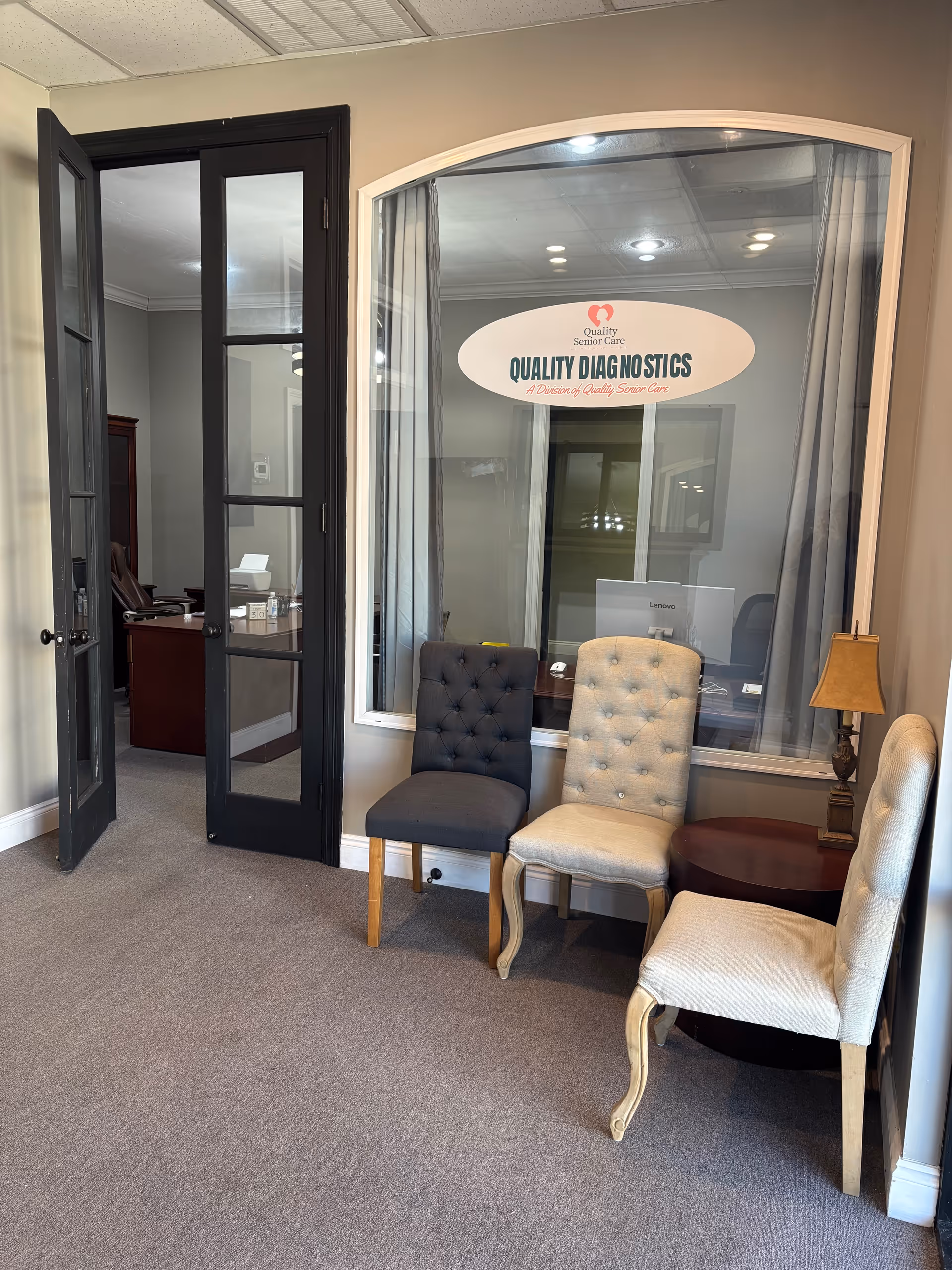 Small waiting area with four upholstered chairs beside a large window