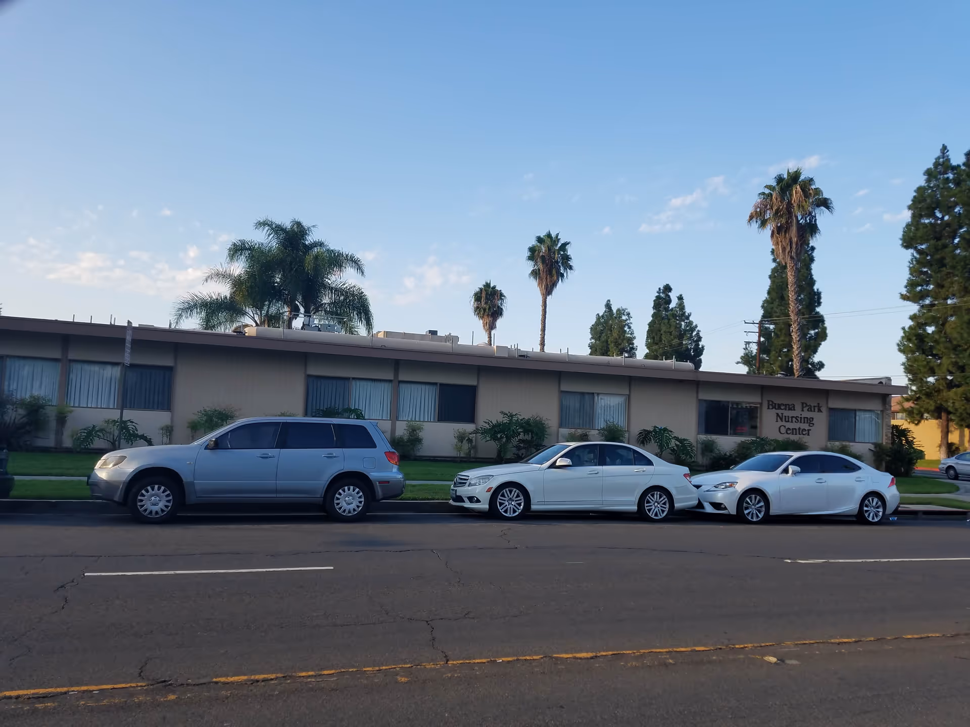 Front exterior of Buena Park Nursing Center with parked cars along the curb.