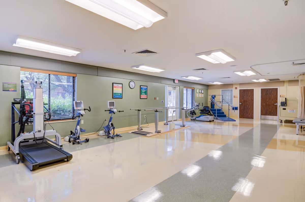 Interior fitness room with treadmills, stationary bikes, and parallel bars.