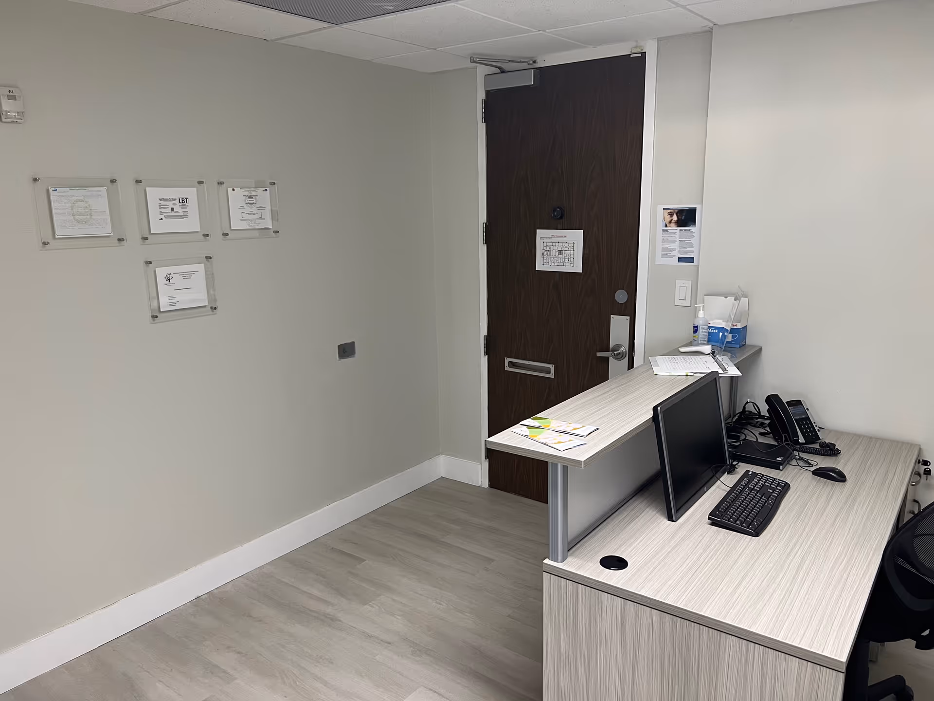 Reception desk with computer, phone, and papers inside a facility office.