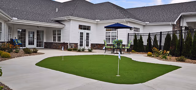 Astoria facility courtyard with a green putting area, outdoor seating under an umbrella.