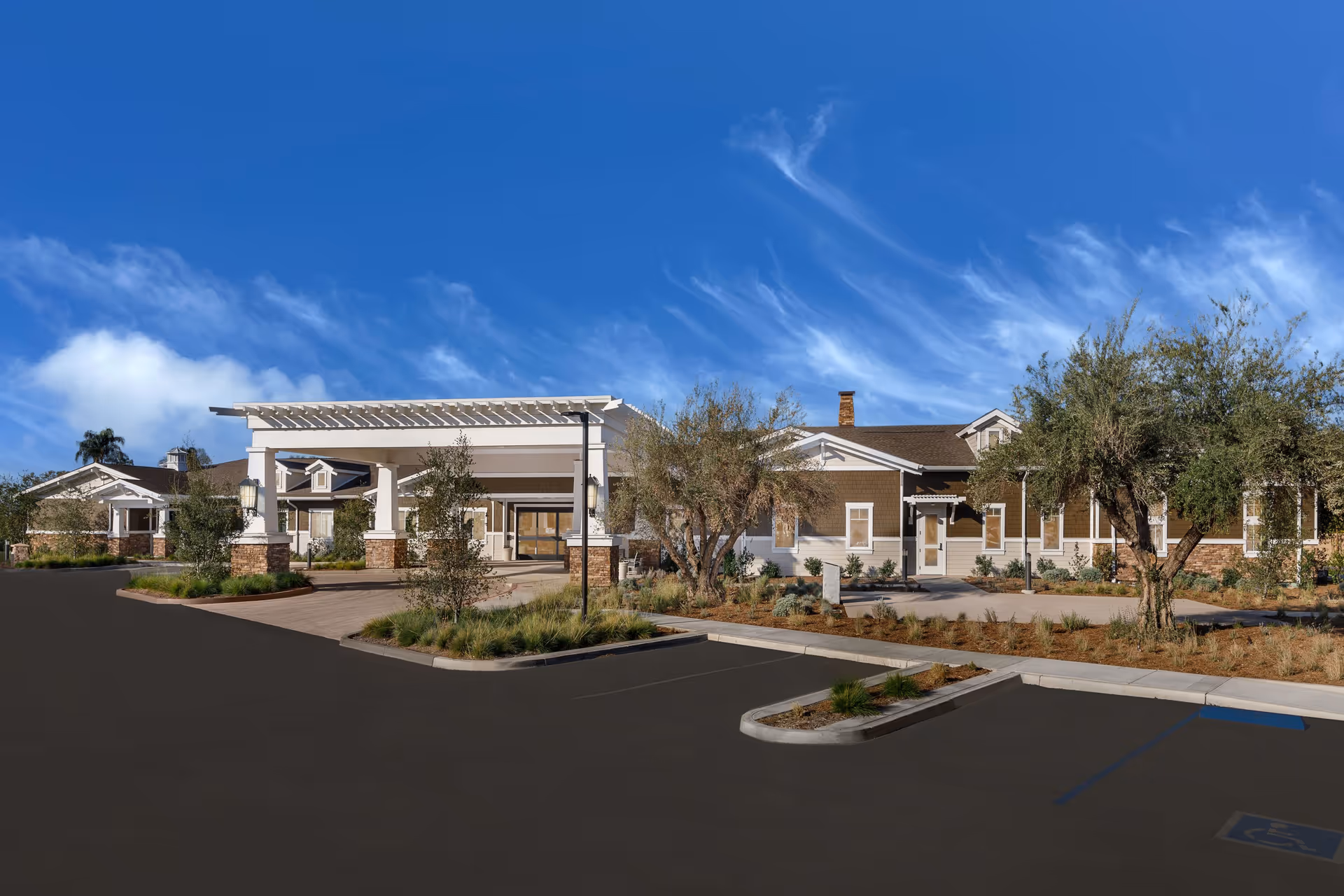 Exterior view of Clearwater at North Tustin senior living facility showing a single-story building with a covered entrance, landscaped surroundings, and a clear blue sky.