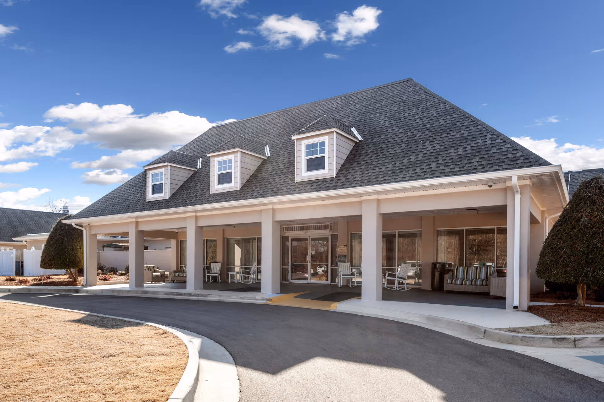 Front view of a single-story senior living facility with a covered porch and seating.